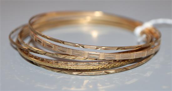 A 9ct gold narrow bangle with engine-turned decoration and seven other narrow bangles.